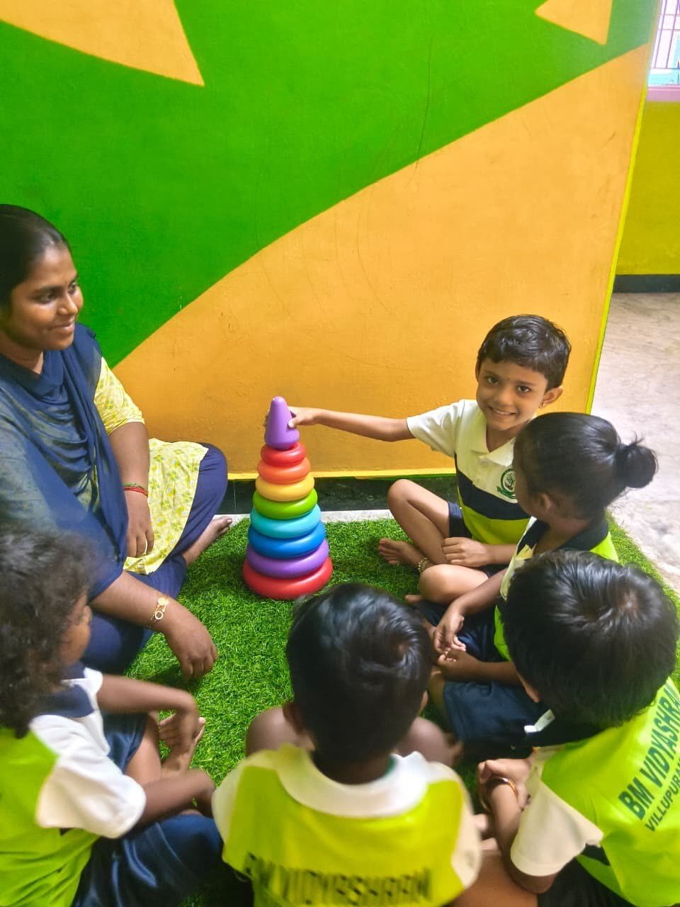 Children playing a colour-matching stacking ring activity at BM Vidyashram